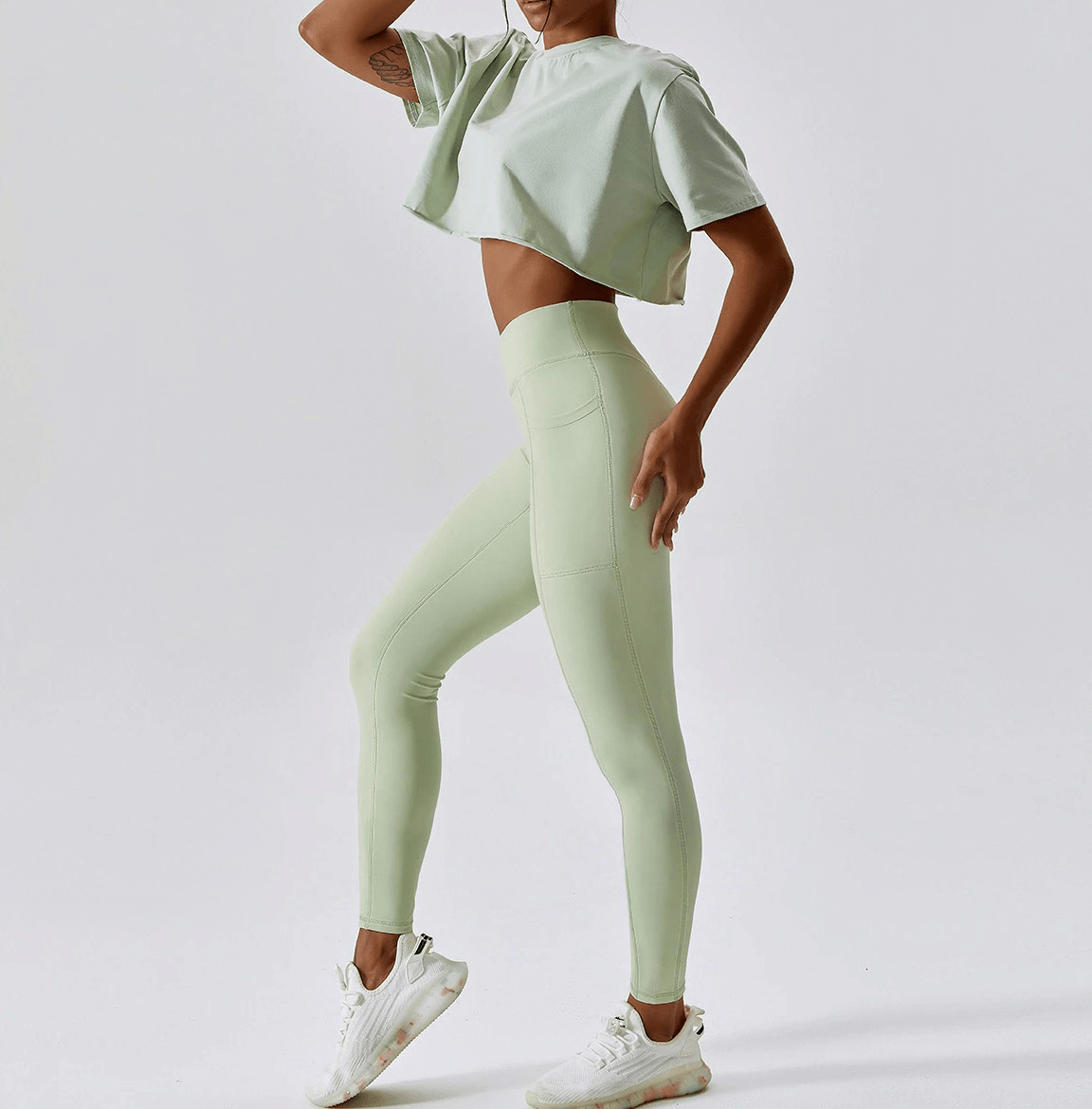 Woman wearing a sports loose crop top and leggings, perfect for yoga, running, and training.